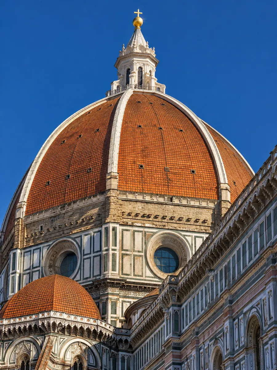 Brunelleschi's dome seen from the street, red tiles and white marble ribs against a blue sky